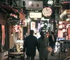 A man and a woman are posing comically in a brightly lit urban setting at night wearing novelty glasses that say 2021