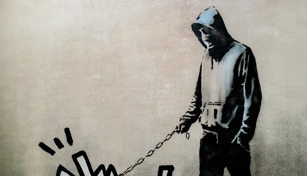 The image shows a monochromatic stenciled graffiti art piece of a person in a hooded top holding a chain that extends to a drawn-out burst of lines to their right all against a textured wall