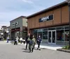 A group of smiling people with shopping bags are posing in front of the Woodbury Common Premium Outlets sign