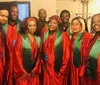 A group of people are smiling for the camera wearing matching red and green choir robes