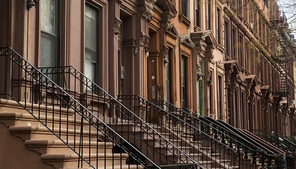 The image shows a row of classic brownstone houses with ornate stoops and iron railings characteristic of a historic urban neighborhood