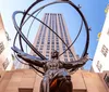 The image shows the Atlas statue in front of the Rockefeller Center in New York City with the art-deco style skyscraper towering in the background