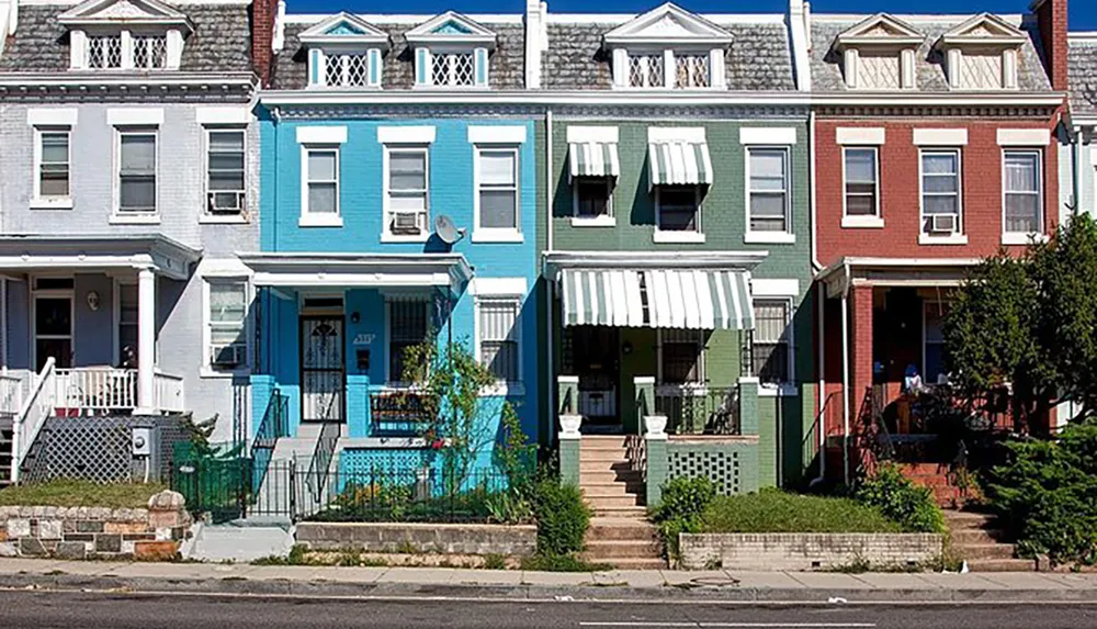 A colorful row of urban townhouses displaying individual character with their varying hues and front porch designs