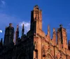 The image shows a gothic-style building with intricate spires against an evening sky accompanied by the waxing crescent moon