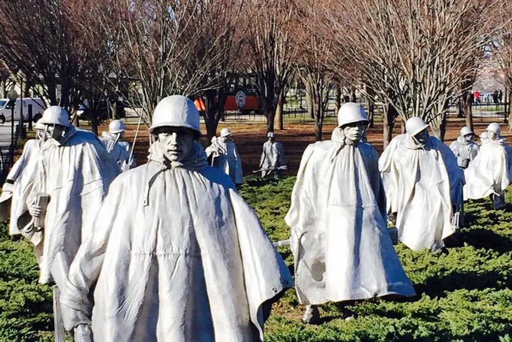 The image features a group of statues representing soldiers clothed in ponchos that give an impression of a patrol walking through a field