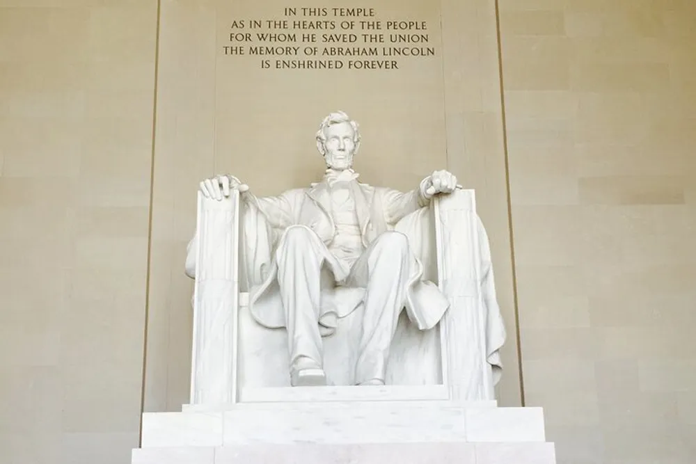 The image shows the iconic statue of Abraham Lincoln seated in contemplation at the Lincoln Memorial in Washington DC with an inscription above