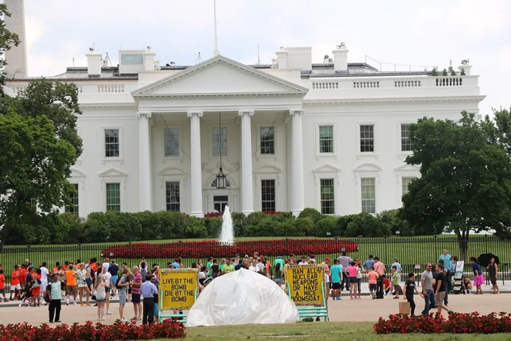 The image shows tourists and protesters in front of the White House with signs advocating for peace and nuclear disarmament