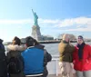 Tourists on a boat are viewing and taking photos of the Statue of Liberty