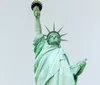 The photo shows a close-up view of the Statue of Liberty focusing on the head and crown with a raised torch visible to the left