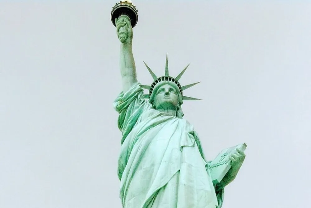 The image shows the Statue of Liberty a colossal sculpture on Liberty Island in New York Harbor symbolizing freedom and welcoming visitors immigrants and returning Americans