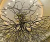 The image shows a large intricately detailed tree sculpture with sprawling branches located inside a room with a curved ceiling and soft lighting