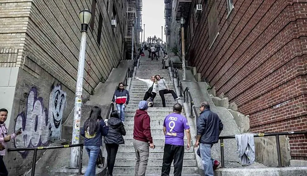 People are posing for photos and enjoying themselves on a steep urban staircase flanked by brick buildings