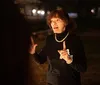 A woman is animatedly speaking outdoors at night possibly addressing a group while gesturing with her hands