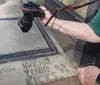 A person is holding a camera next to a dirty doormat with the phrase Wear your kicks stenciled on it
