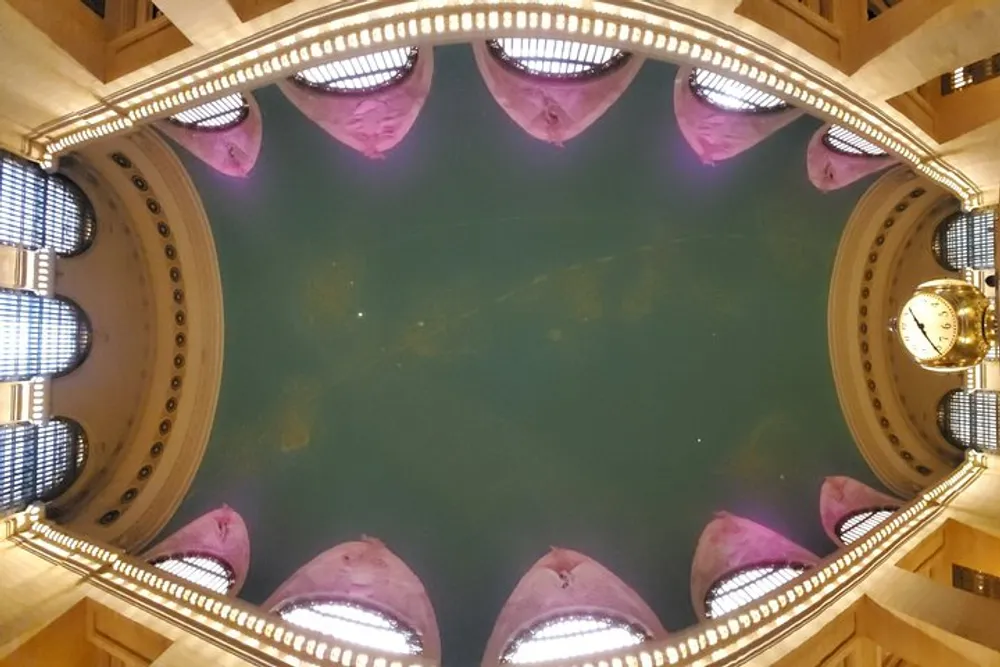The image shows a ceiling with an ornate oval mirror reflecting a chandelier and purple-tinted architectural details
