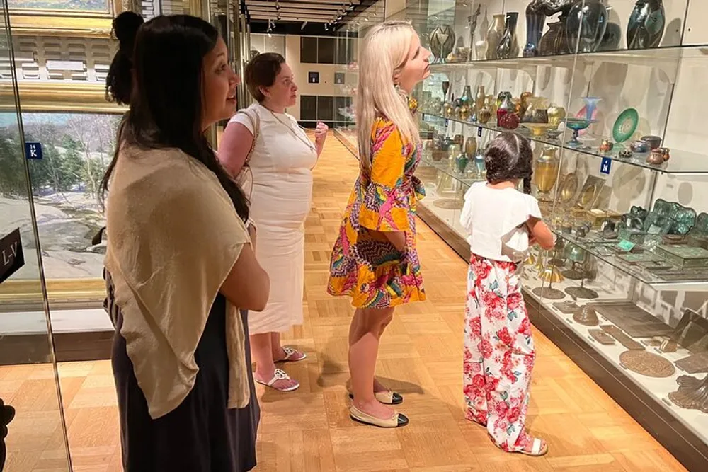 A group of people including a child are observing glass exhibits at a museum