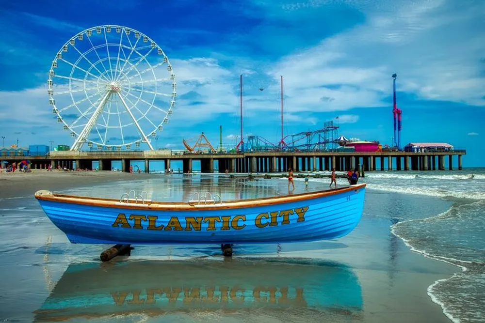 A lifeboat with the words Atlantic City painted on its hull is positioned on a sandy beach against the backdrop of a pier with amusement park rides including a Ferris wheel under a partly cloudy sky
