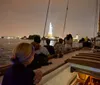 People are enjoying a nighttime sail with a view of a brightly lit city skyline in the background