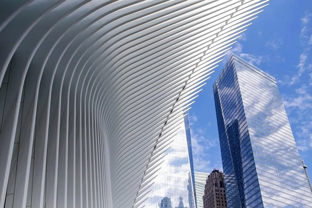 The image features the distinct curved white ribs of the Oculus structure in lower Manhattan contrasting with the surrounding skyscrapers under a blue sky