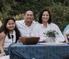 A family of four is smiling and enjoying an outdoor meal together