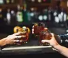 Three people are toasting with whiskey glasses at a bar