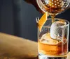 Three people are toasting with whiskey glasses at a bar