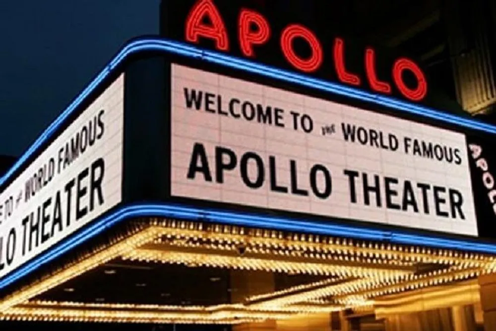 The image shows the illuminated marquee of the world-famous Apollo Theater at night