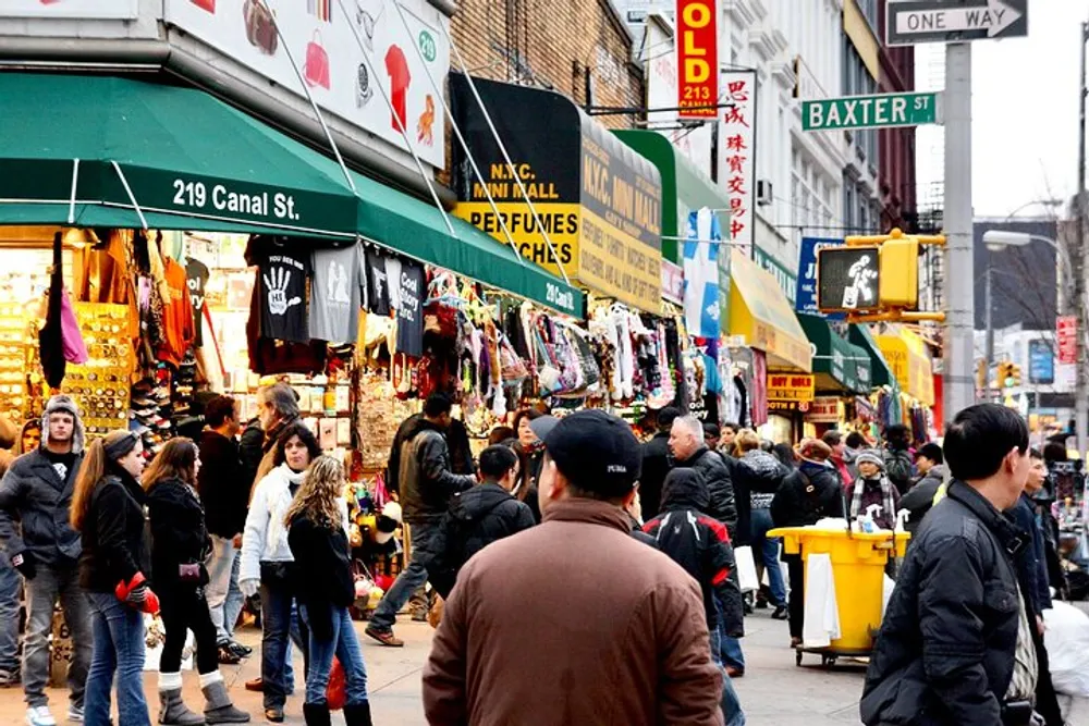 This image depicts a bustling street scene with pedestrians and a variety of colorful store fronts along Canal Street in an urban environment