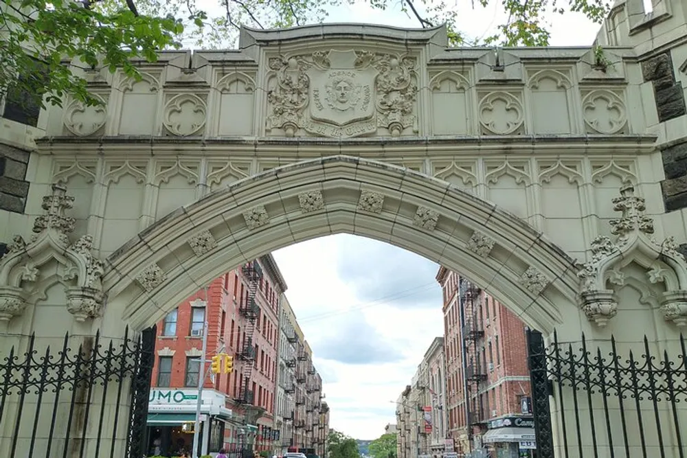 The image showcases an ornate stone archway over a street displaying intricate carvings and a coat of arms creating a historic atmosphere within an urban environment