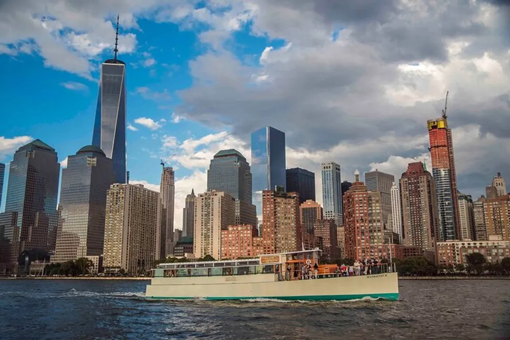 A ferry is cruising along the water in front of a sprawling urban skyline under a cloudy sky