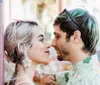 A couple shares an affectionate moment under an ornate arched passageway with a staircase in the background