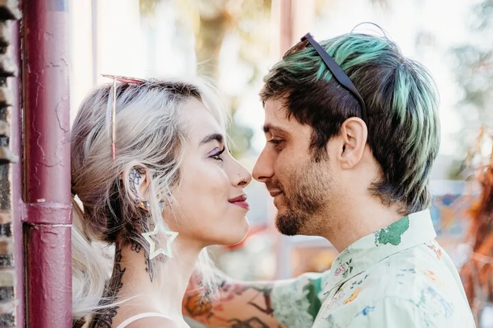 A couple with dyed hair and tattoos gazes affectionately into each others eyes