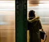 A person waits on the platform as a blur of a moving train creates a dynamic backdrop