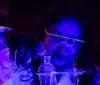 Two people wearing lab coats and safety glasses are working with glowing green chemicals in a laboratory setting