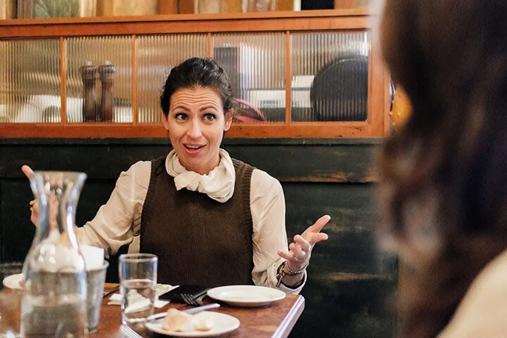 A woman is having an animated conversation at a dining table in a restaurant