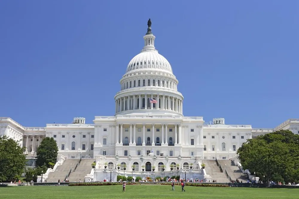 The image shows the United States Capitol a symbol of the American democracy and the home of the United States Congress on a clear day with visitors on its grounds