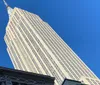 The image shows the towering facade of a skyscraper against a clear blue sky