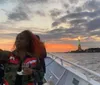 People on a boat are taking photos of the Statue of Liberty at twilight