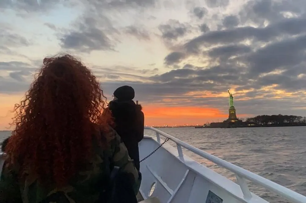 A person is gazing at the Statue of Liberty from a boat at sunset