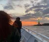 People on a boat are taking photos of the Statue of Liberty at twilight