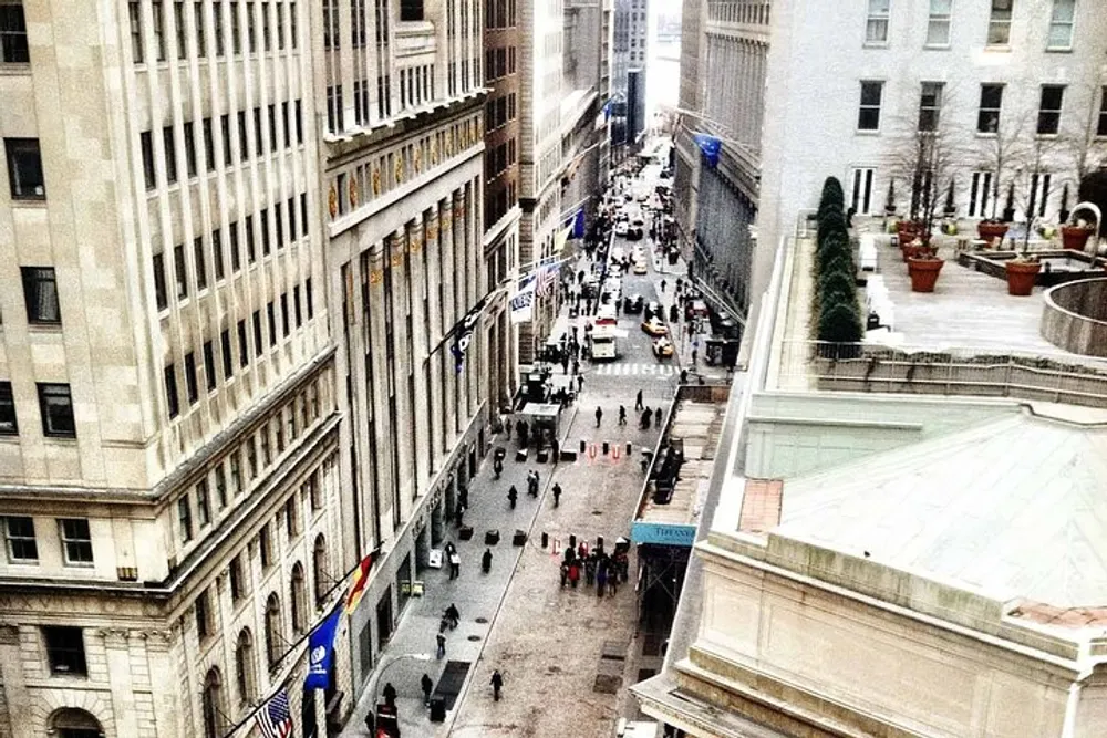 The image shows an elevated view of a busy urban street flanked by tall buildings bustling with cars and pedestrians