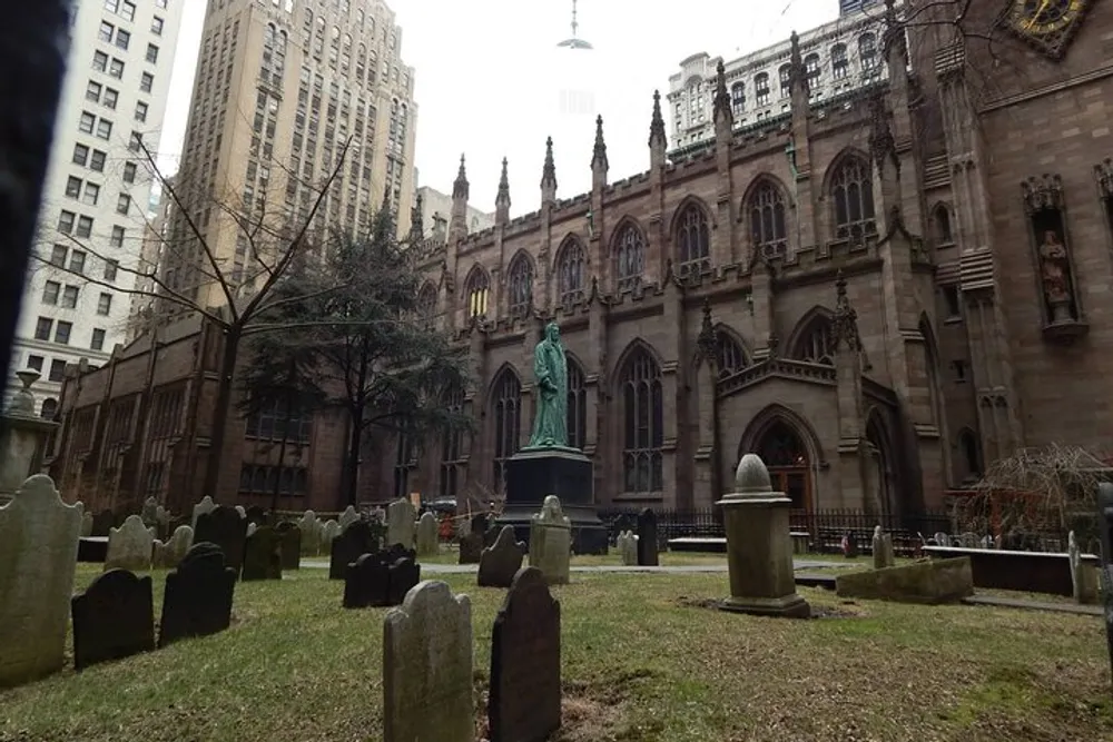 The image shows an old church with Gothic architecture and a graveyard in the foreground nestled among high-rise buildings