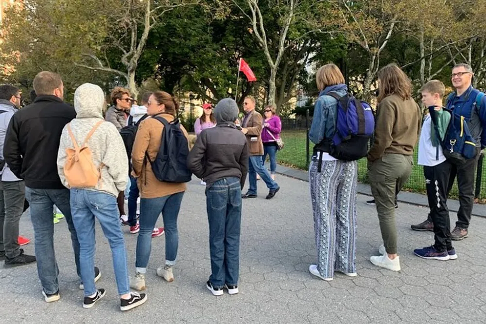 A group of people appear to be participating in an outdoor guided tour with the guide holding a red flag for easy visibility