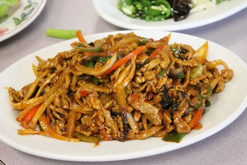 The image shows a plate of stir-fried possibly Chinese cuisine with sliced vegetables and meat in a glossy sauce