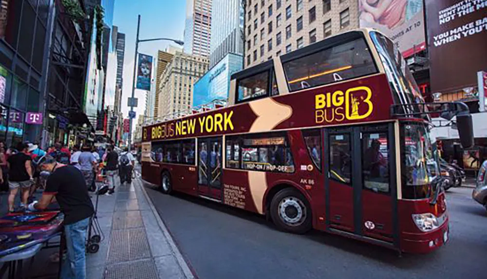 The image shows a bustling city scene with a red double-decker sightseeing bus labeled BIG BUS NEW YORK surrounded by pedestrians and towering advertisements in what appears to be Times Square