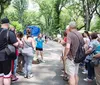 A group of people is attentively listening to a tour guide in a lush park setting