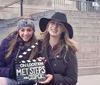 Two smiling women pose for a photo on some steps with one holding a clapperboard labeled MET STEPS GOSSIP GIRL