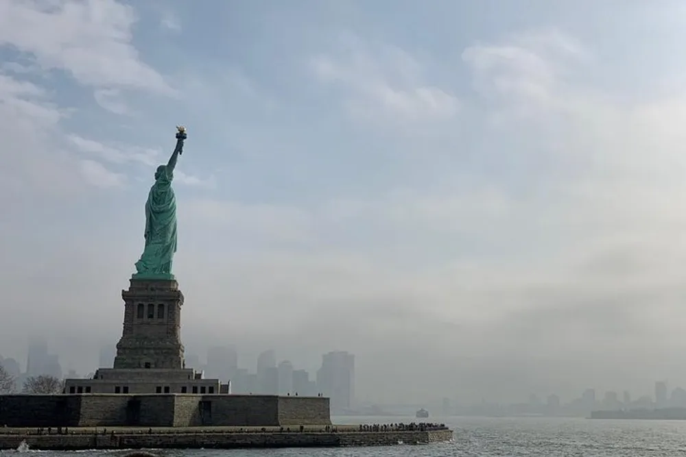 The Statue of Liberty stands tall against a misty city skyline backdrop