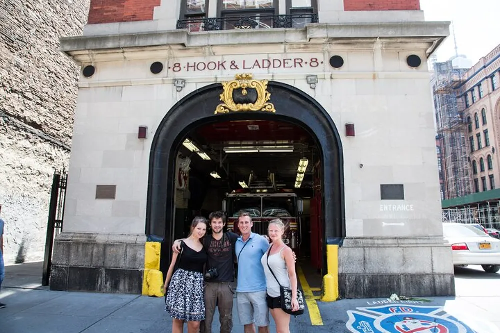 Three people are posing for a photo in front of the Hook  Ladder 8 firehouse known for its appearance in the Ghostbusters movies