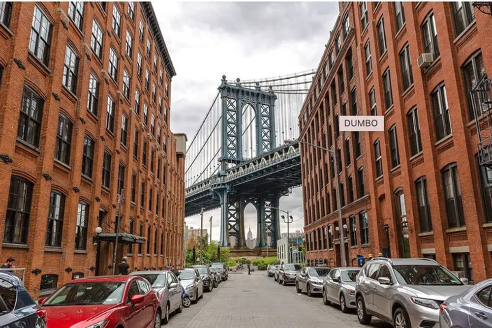 This image features a classic view of the Manhattan Bridge framed by the brick buildings of DUMBO a neighborhood in Brooklyn New York